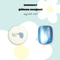 A product graphic for Enoi Summer Glass magnet gel in a blue MG158 shade. It shows a round white potted gel containing a light blue glittery gel  and a glossy blue nail sample. Available on Mellow Edit. 